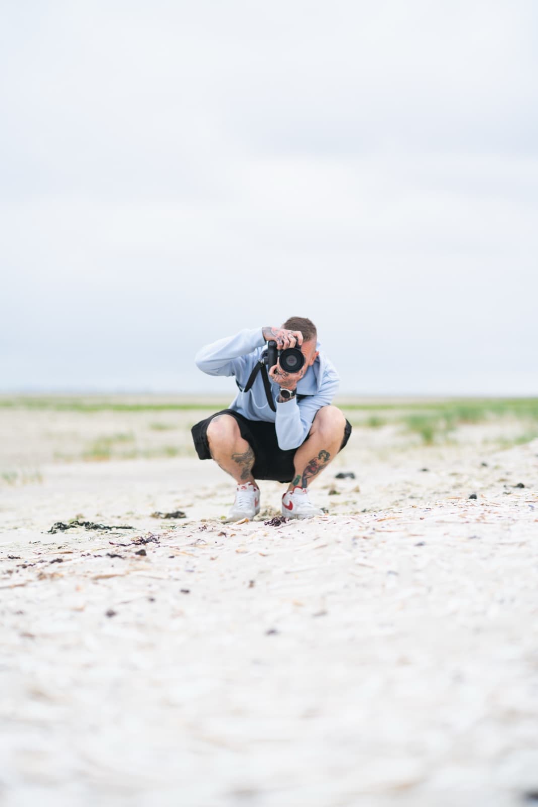 Daniel Boberg fotografiert in der Hocke am Strand