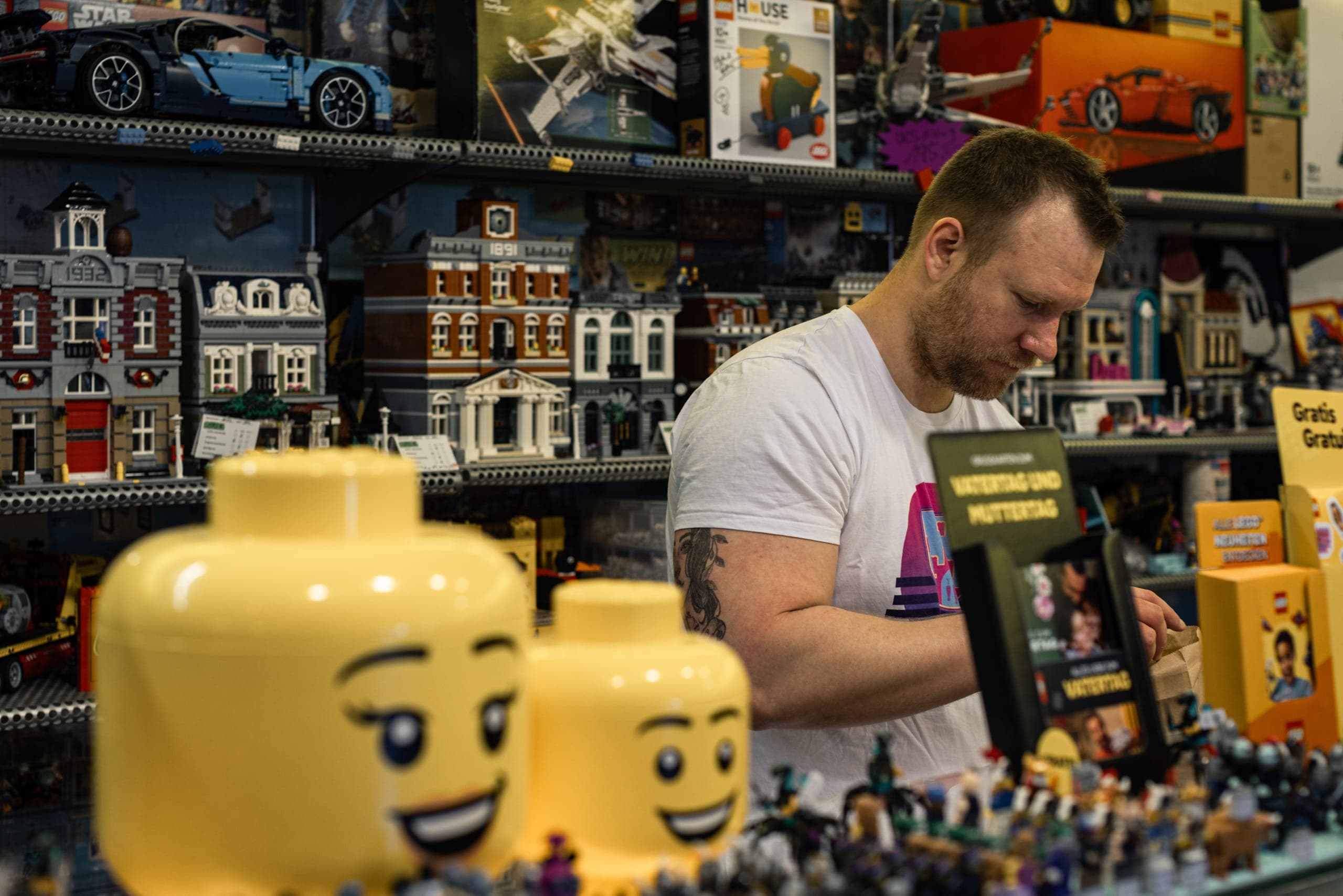 Person räumt hinter großen Minifiguren-Köpfen ein