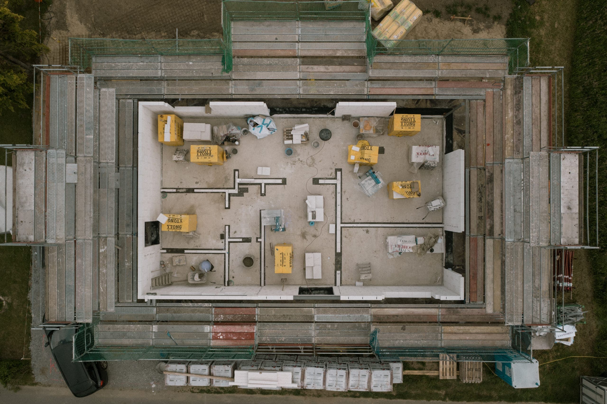 Drohnenblick von oben auf den Rohbau zwischen Gerüst und Baumaterial