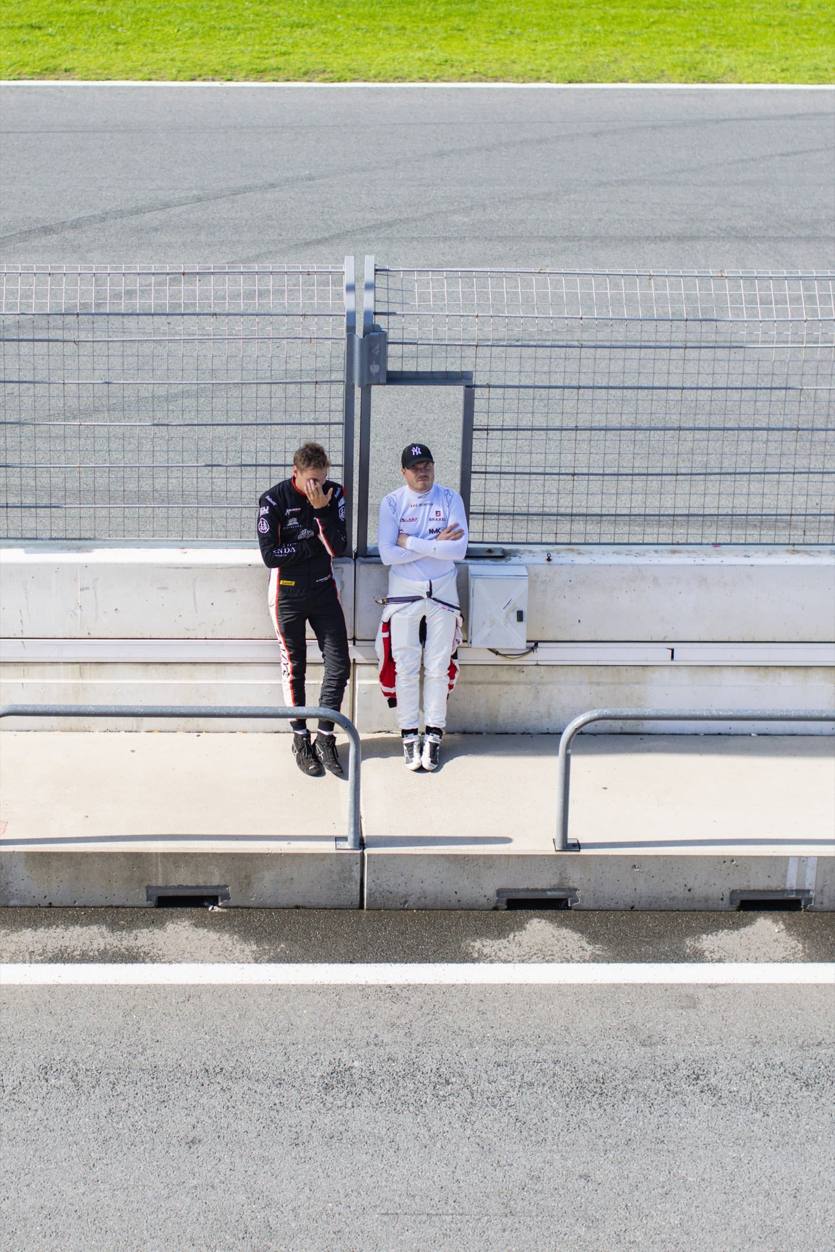 Zwei Rennfahrer lehnen an der Boxenmauer des Circuit Zandvoort