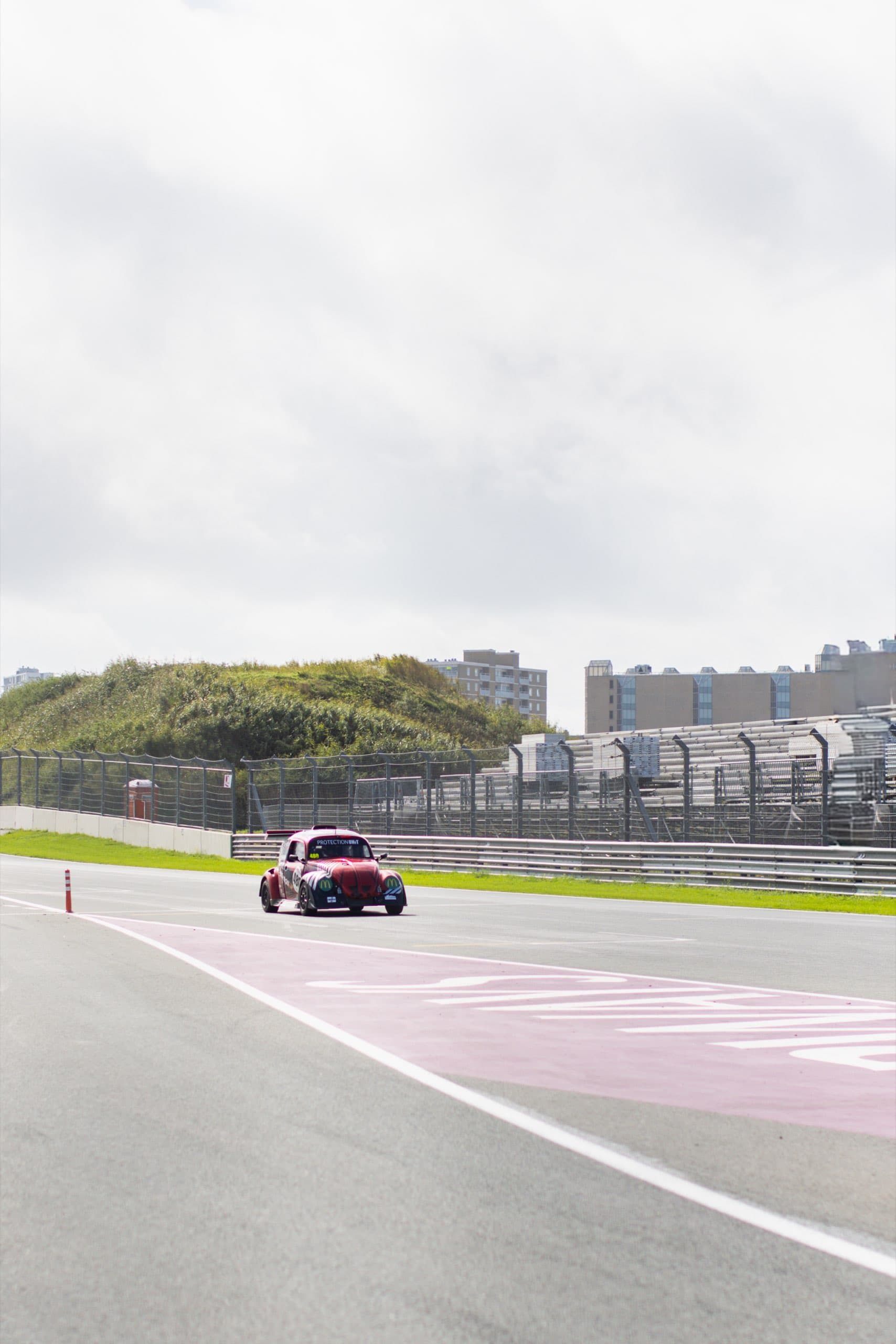 Roter Käfer-Rennwagen auf der Strecke des Circuit Zandvoort vor den Dünen