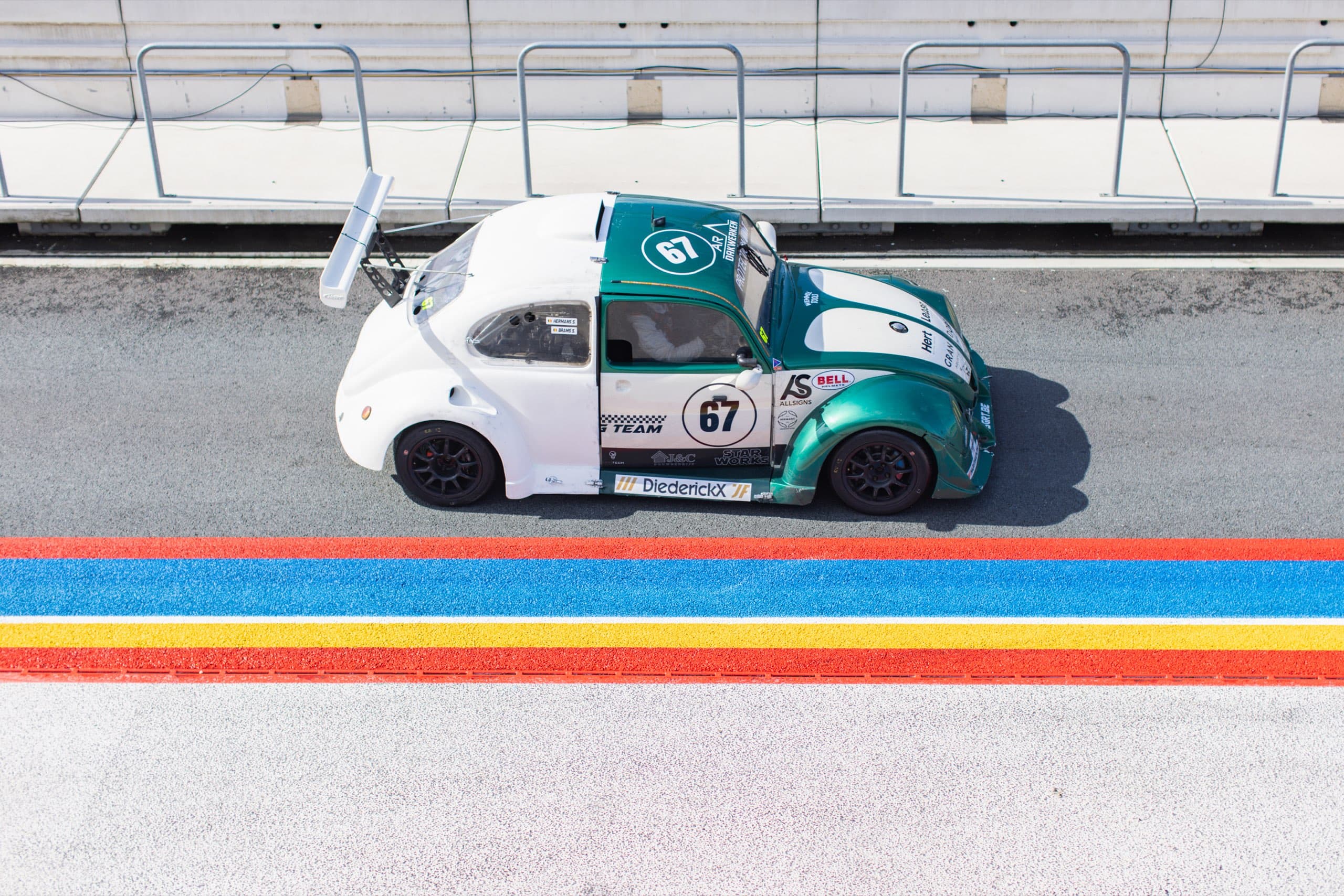 Grün-weißer Käfer-Rennwagen in der Boxengasse, von oben