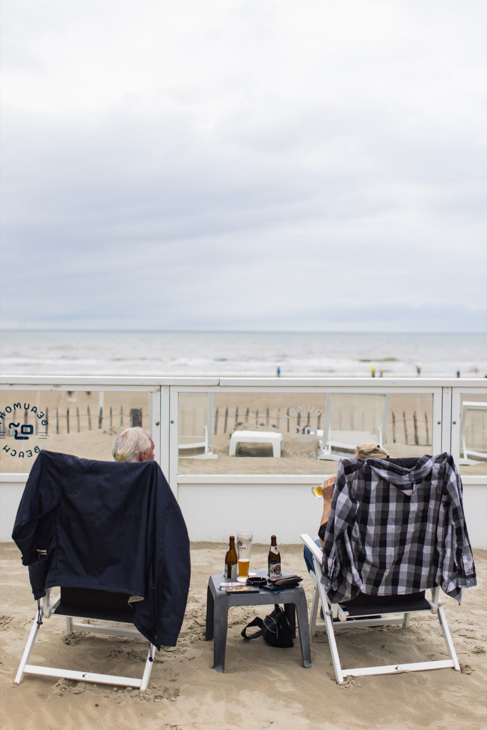 Liegestühle mit Jacken und Getränken am Strand von Zandvoort