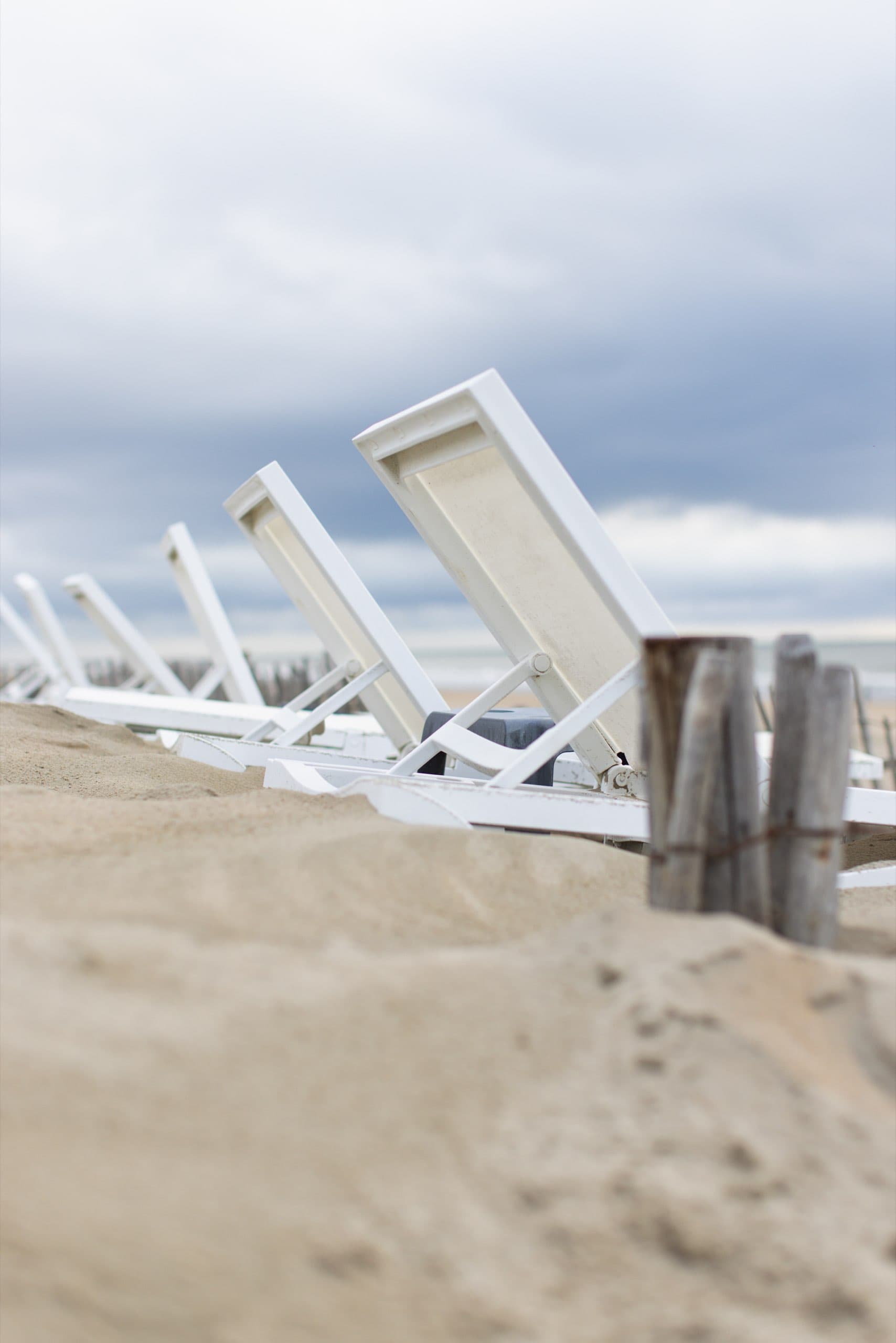 Weiße Strandliegen im Sand