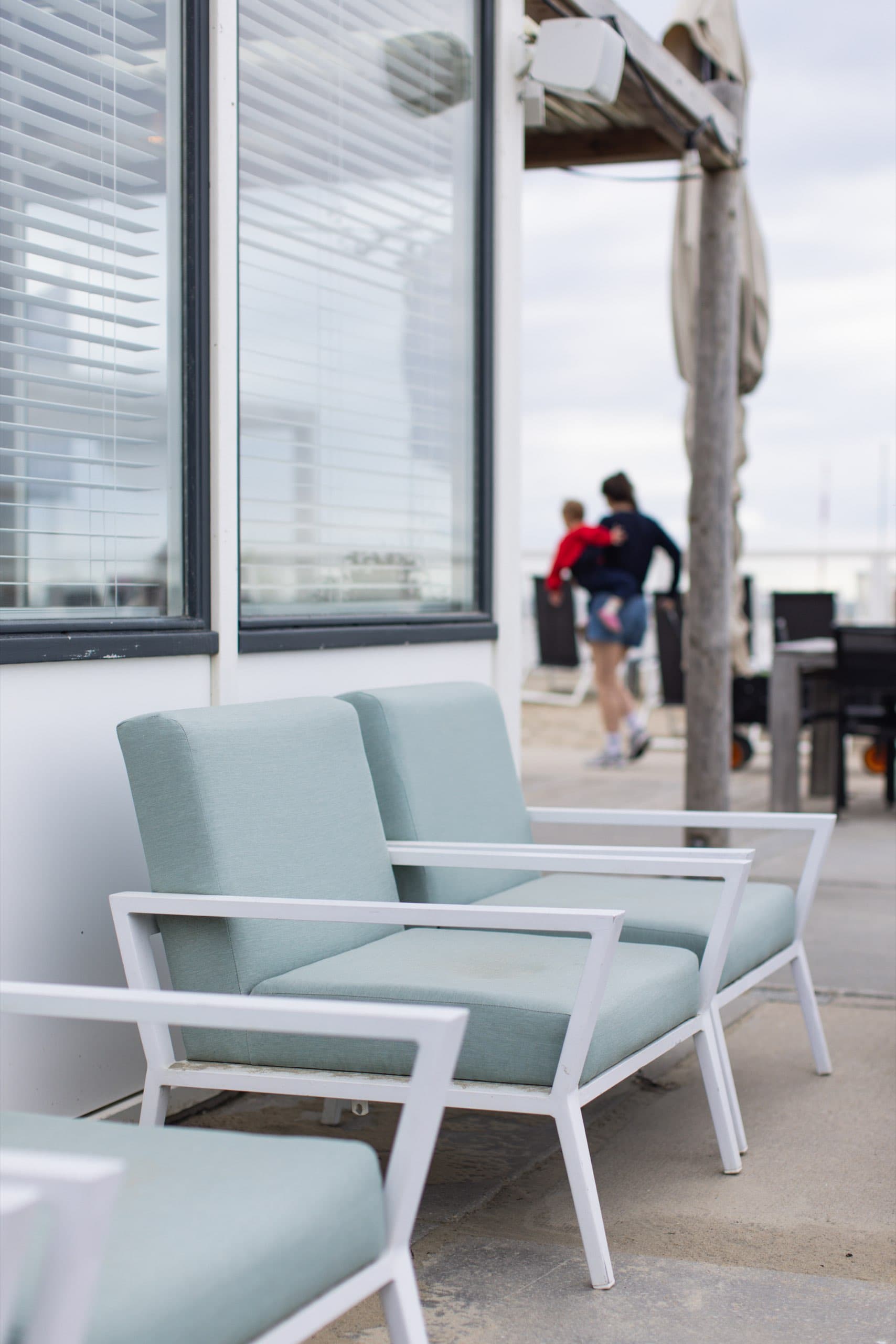 Mintfarbene Loungesessel vor einem Strandcafé