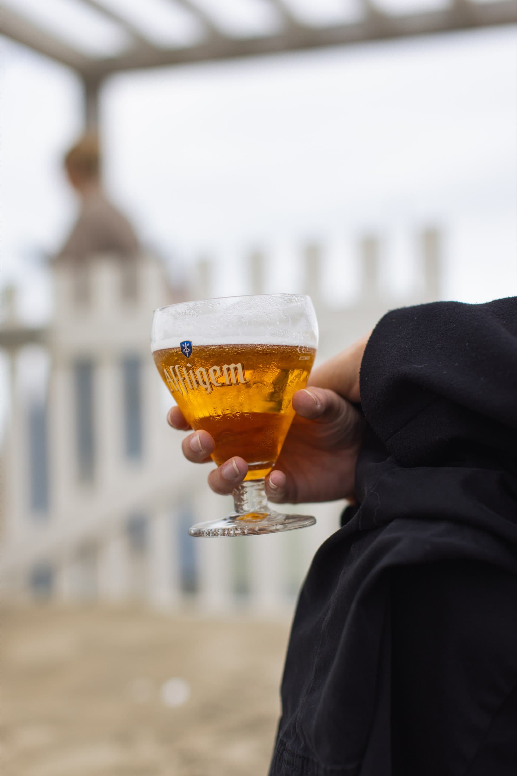 Glas Bier vor dem weißen Zaun eines Strandpavillons
