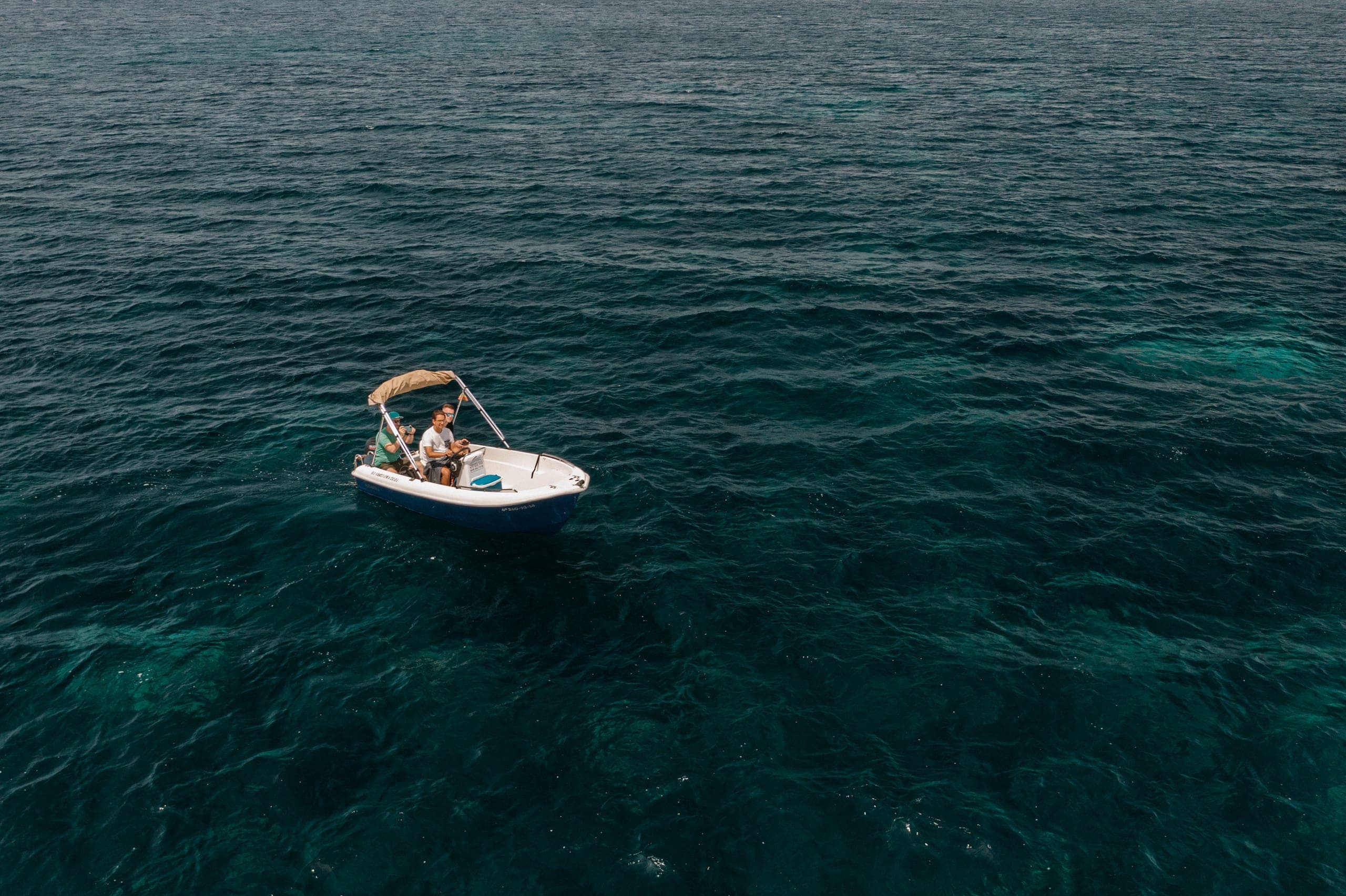 Kleines Motorboot auf dem tiefblauen Meer von oben